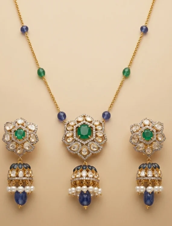 Ornate gold jewelry set featuring a central green gemstone with surrounding clear stones; includes a matching necklace with blue and green beads and three pendant earrings with pearl drops.