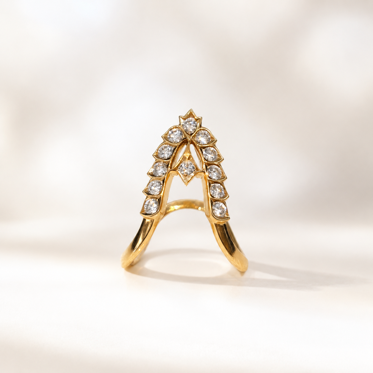 Gold ring featuring an arched, diamond-encrusted centerpiece with diamonds along the crown area.