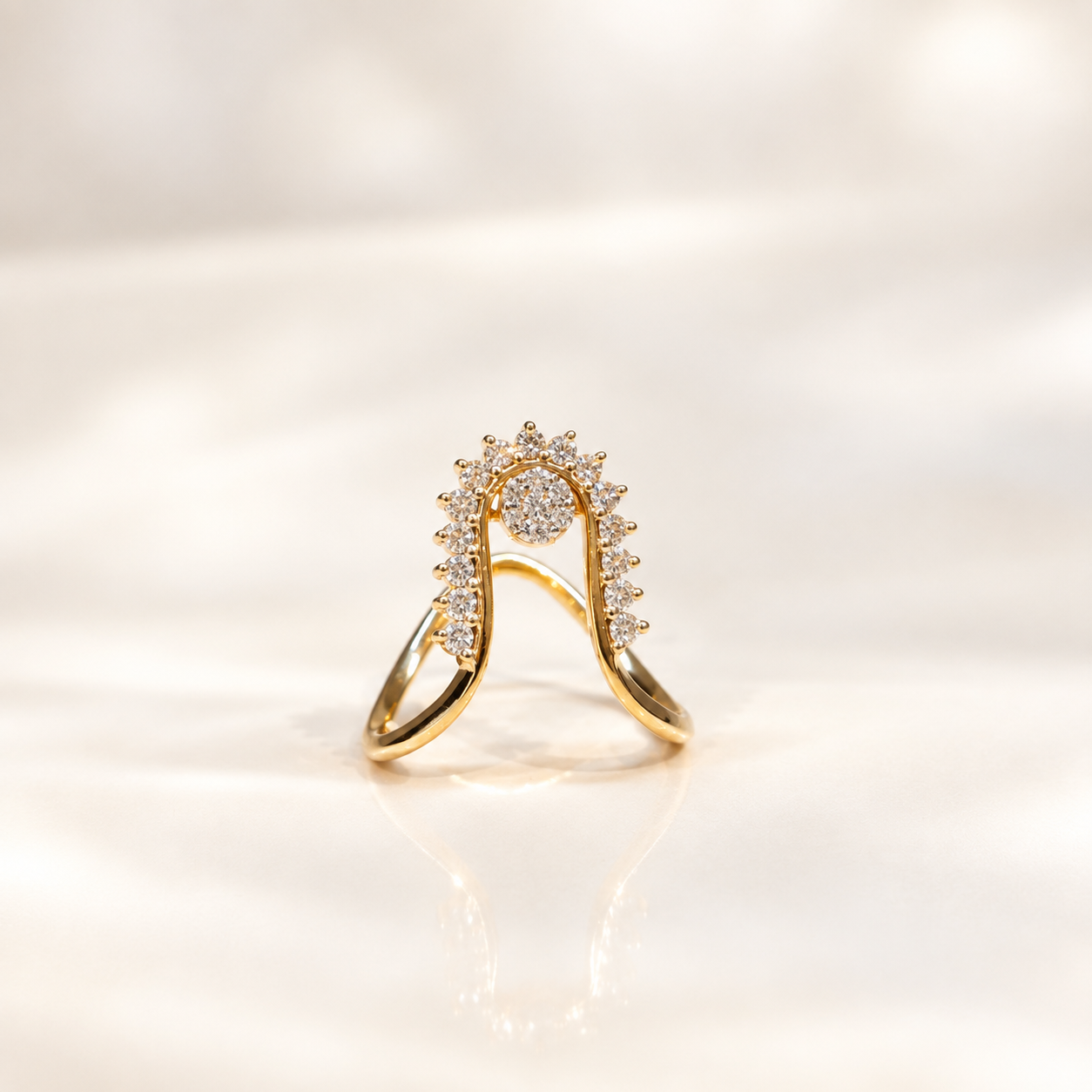 Gold ring with a curved halo setting studded with diamonds, resting on a reflective surface.