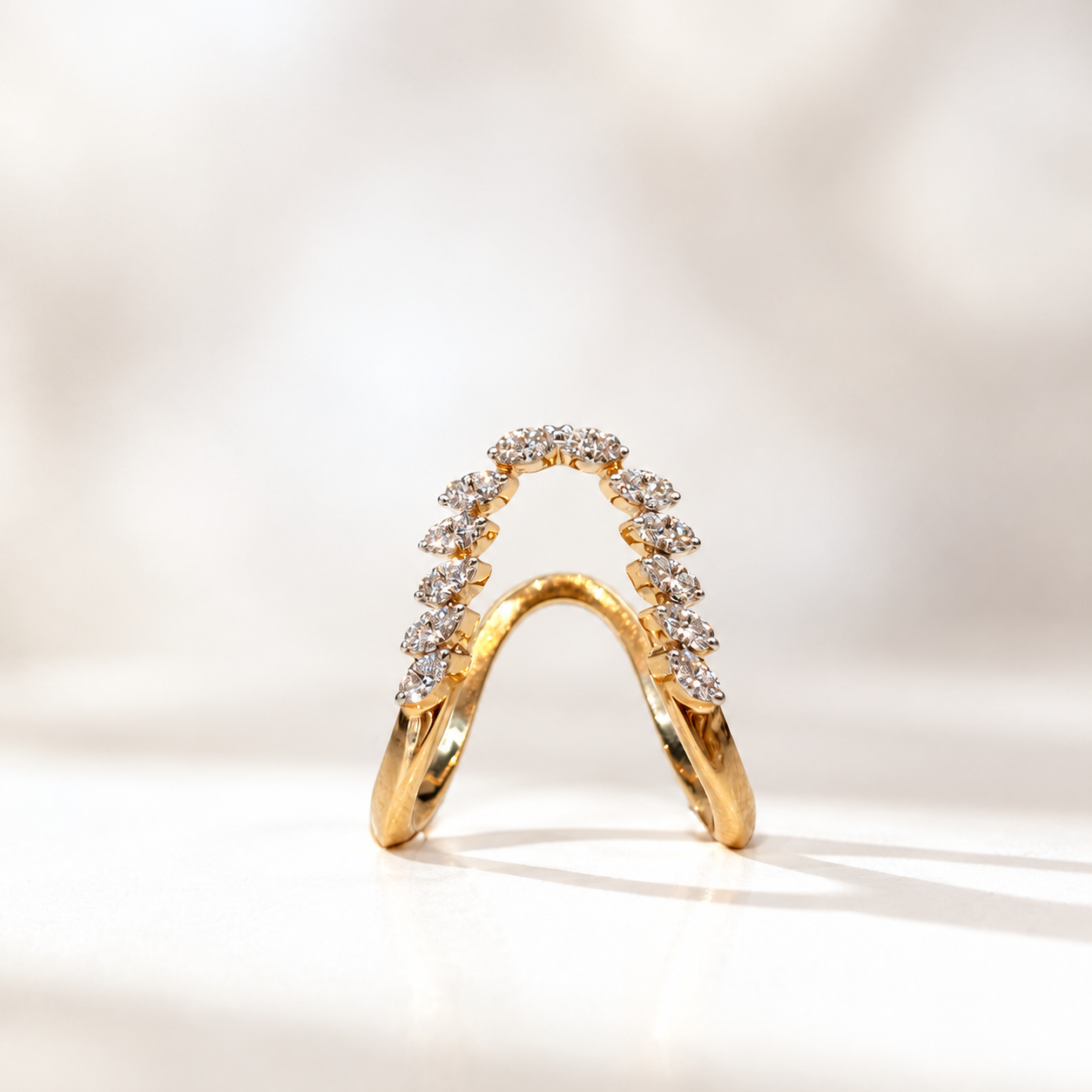 Gold ring with two bands forming a curved arch adorned with diamonds.