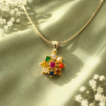 Gold star-shaped pendant with multicolored gemstones on a gold chain, resting on green satin fabric