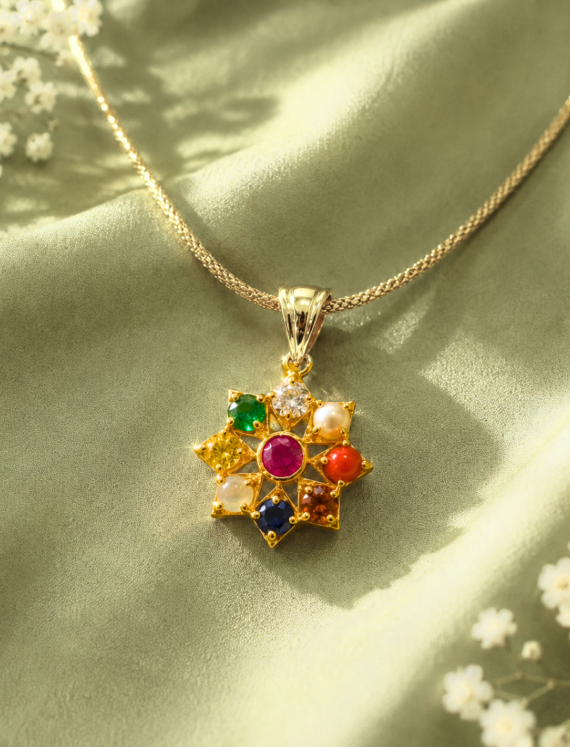 Gold star-shaped pendant with multicolored gemstones on a gold chain, resting on green satin fabric