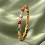 Gold bracelet with square colored gemstones and diamond accents displayed on green satin fabric.