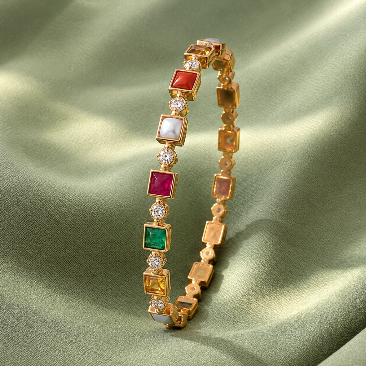 Gold bracelet with square colored gemstones and diamond accents displayed on green satin fabric.