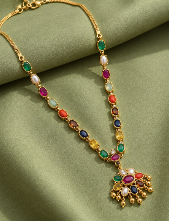 Gold necklace with a multicolored gemstone pendant laid on green satin fabric.
