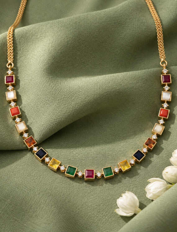 Gold necklace with square multicolor gemstones and diamond accents on green fabric background.