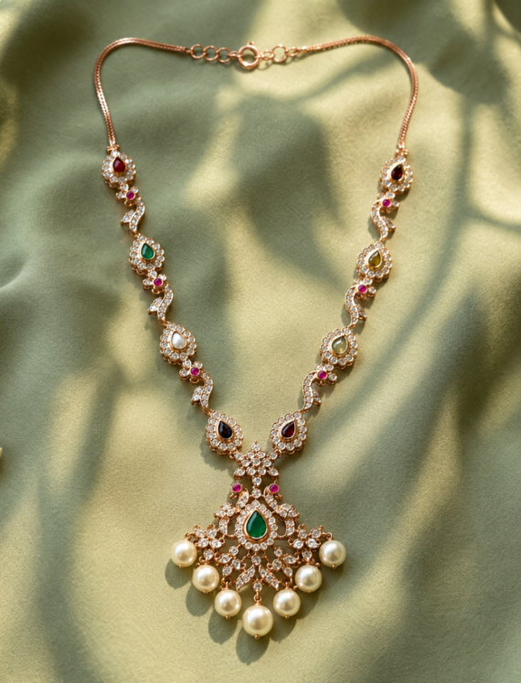 Intricate gold-tone necklace with colorful gemstones and pearl fringe displayed on green satin fabric