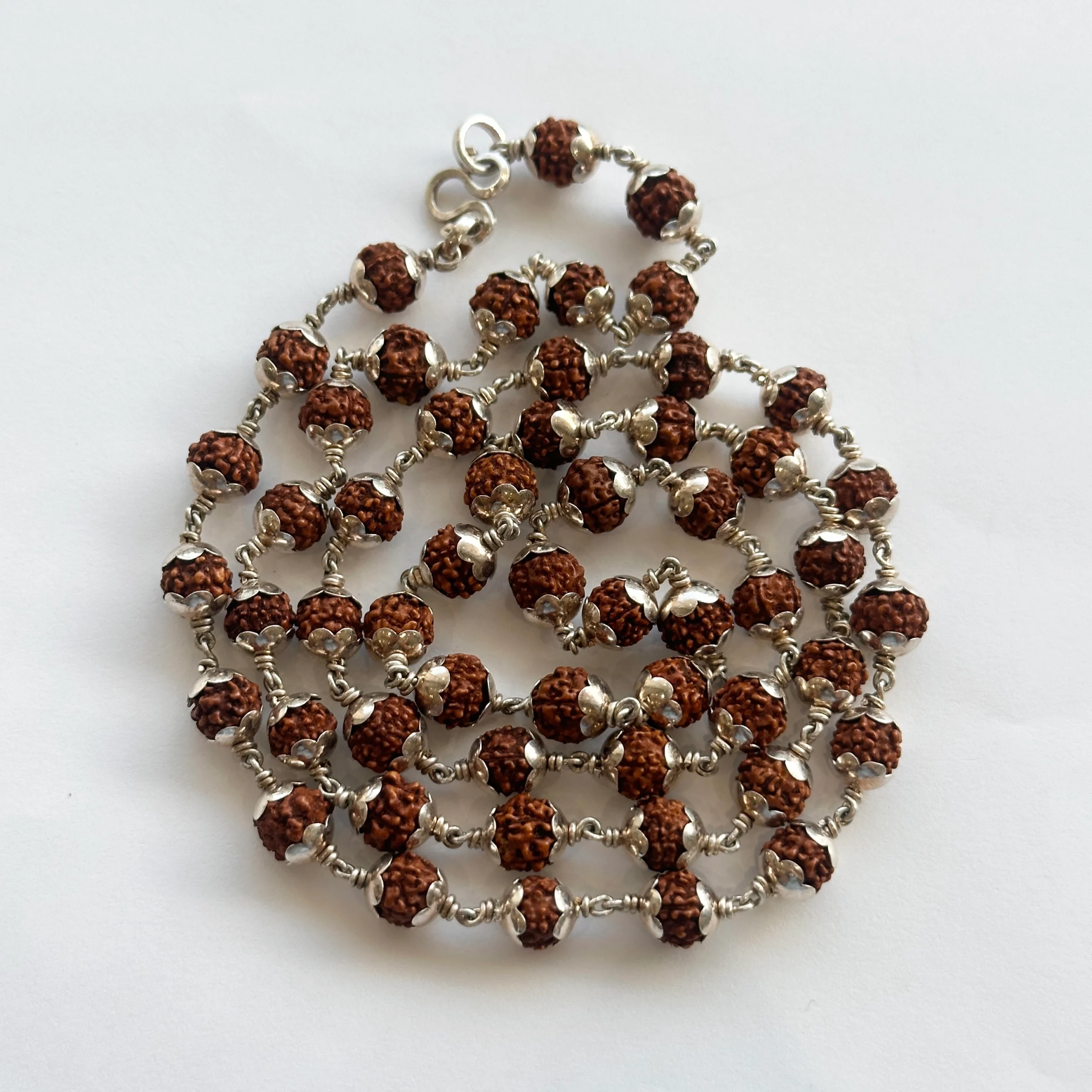 Rudraksha Malai-77-37347 - N Gopaldaas Jewellers Silver-toned beaded necklace with brown textured beads and small silver flower spacers, laid in a tangled cluster.