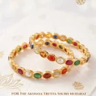 Gold bracelet with multicolored gemstone links arranged in a circular pattern on a light fabric background, logo in the corner.